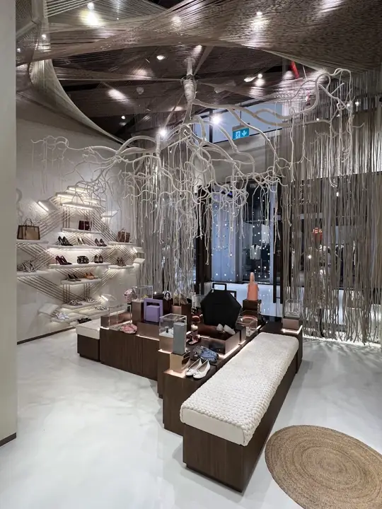 Inside Naseej: a curved lounge bench under arched alcoves lined with rose-gold woven shelving