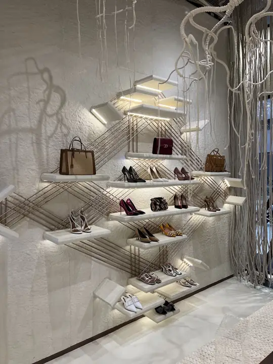 Shoes and bags arranged on Naseej’s rose-gold lattice shelving